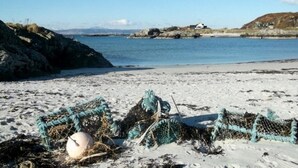 Una playa con redes de pesca y una boya en la arena.