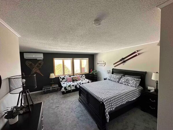 A bedroom with a bed, bedside tables, a window, and a wall-mounted rack.