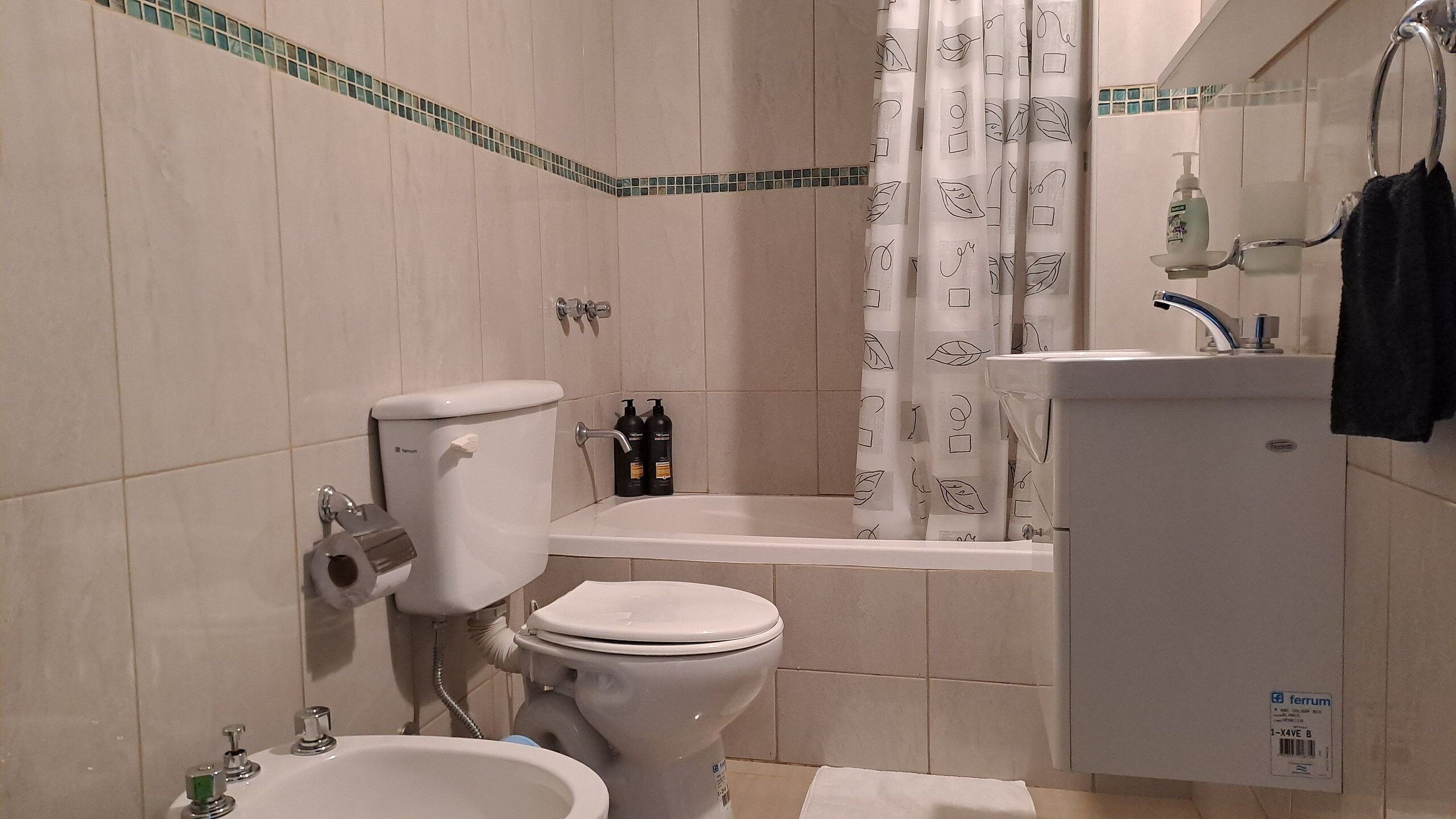 Une salle de bain avec deux toilettes, un bidet, un lavabo et un espace douche.