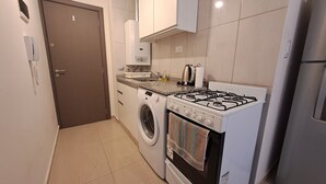 A compact kitchen with a washing machine, a gas stove, and a built-in oven.