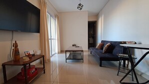 A modern living room with a flat-screen TV, a sofa, a coffee table, and a dining table.