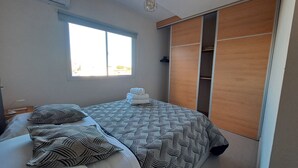 A bedroom with a bed, pillows, a window, and a wardrobe.