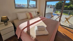 Et soveværelse med seng, sengeborde, et vindue og en balkon med stole.
