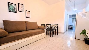 A living room with a brown sofa, a dining table with chairs, and three framed leaf artworks on the wall. - Dorados Güemes - Fully accessible at Pichincha (Rosario)
