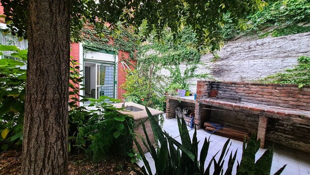 A patio area with a brick barbecue, a window with a green shutter, and lush greenery. - Dorados Güemes - Fully accessible at Pichincha (Rosario)