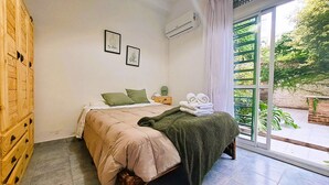 A bedroom with a bed, a nightstand, a window with a view of greenery, and two framed pictures on the wall. - Dorados Güemes - Fully accessible at Pichincha (Rosario)