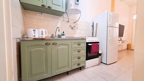 A compact kitchen with green cabinets, a white countertop, a sink, a kettle, a toaster, and a white refrigerator. - Dorados Güemes - Fully accessible at Pichincha (Rosario)