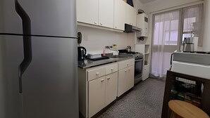 A compact kitchen with white cabinets, a refrigerator, a stove, and a sink. - Hornera Mai - The perfect place (Rosario)