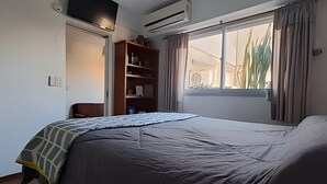 A bedroom with a bed, a wardrobe, a window with curtains, and an air conditioning unit. - Hornera Mai - The perfect place (Rosario)