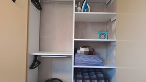 A closet with shelves containing folded clothes, a fan, and a small decorative item. - Hornera Mai - The perfect place (Rosario)