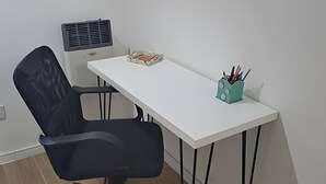 Un'area dedicata al lavoro, con scrivania bianca, sedia da ufficio nera e portapenne color petrolio.