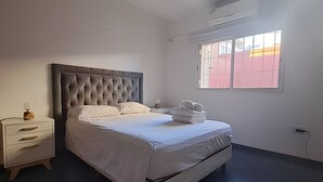 Una camera da letto con un letto grande, un comodino, una finestra e un condizionatore d'aria.