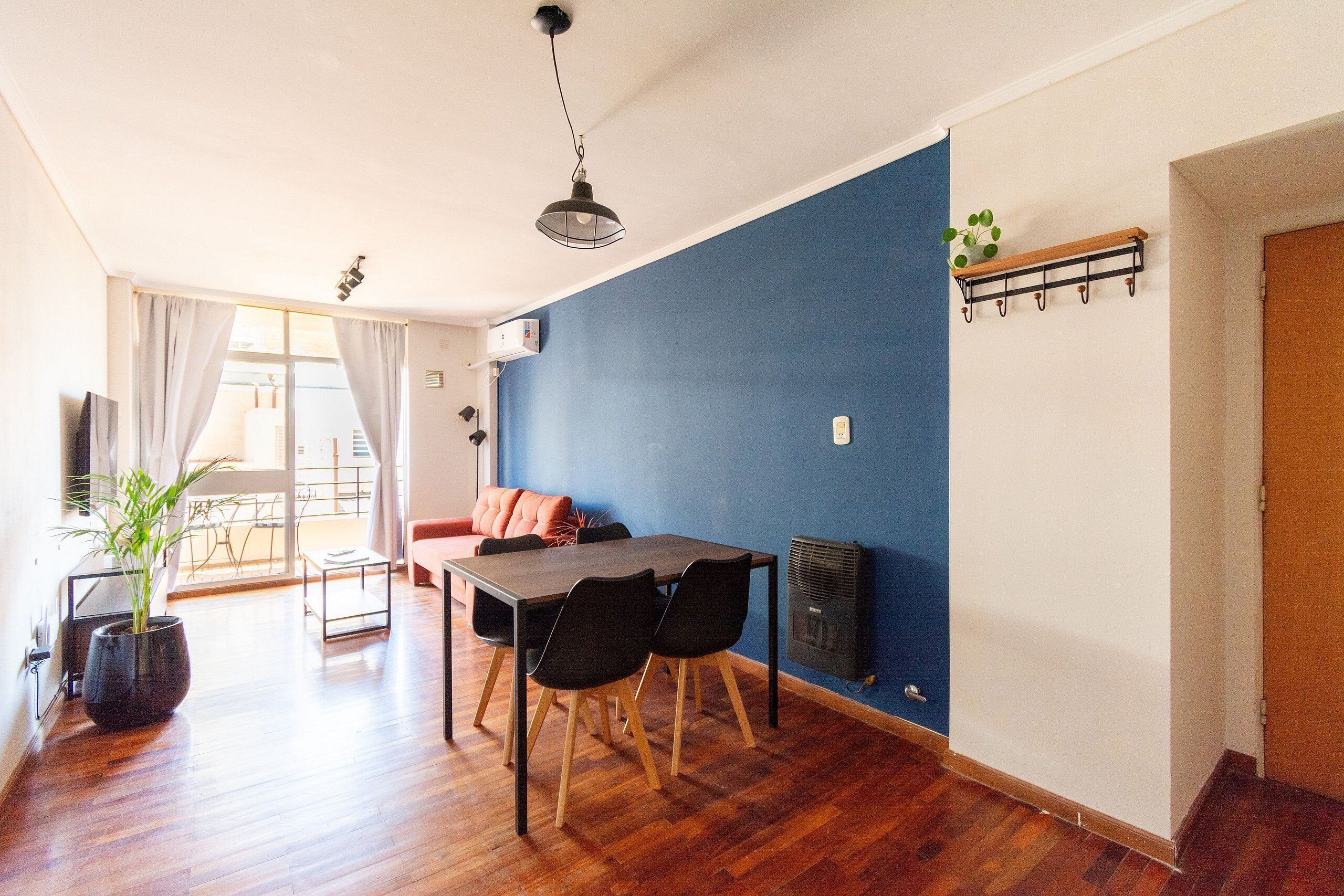 Comedor con mesa y sillas de madera, una planta en maceta y un calentador fijado a la pared.