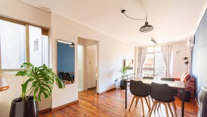 A spacious living area with a wooden floor, a dining table with chairs, and a potted plant. - Hornera Coti - Modern, comfortable, ideal location. (Rosario)