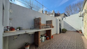 Une cour avec une cheminée en briques, des plantes en pot et un sol carrelé.