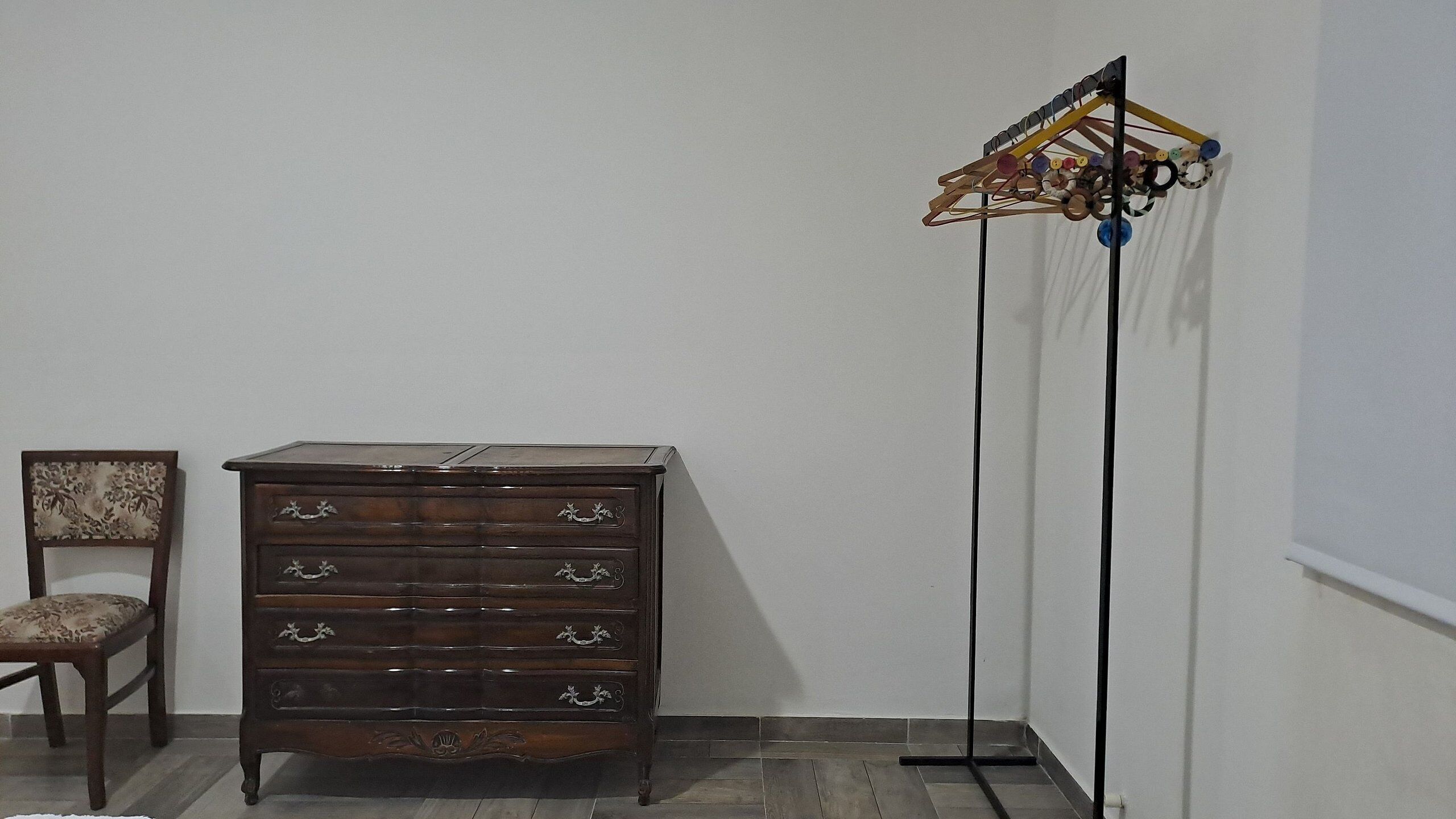 A wooden dresser with multiple drawers and a chair with a patterned cushion.