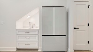 Eine Küche mit einem weißen Kühlschrank, einer weißen Arbeitsplatte und einer weißen Tür.