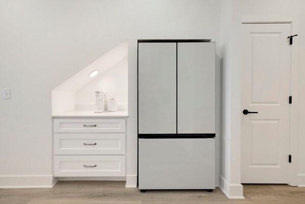 A kitchen with a white refrigerator, a white countertop, and a white door.