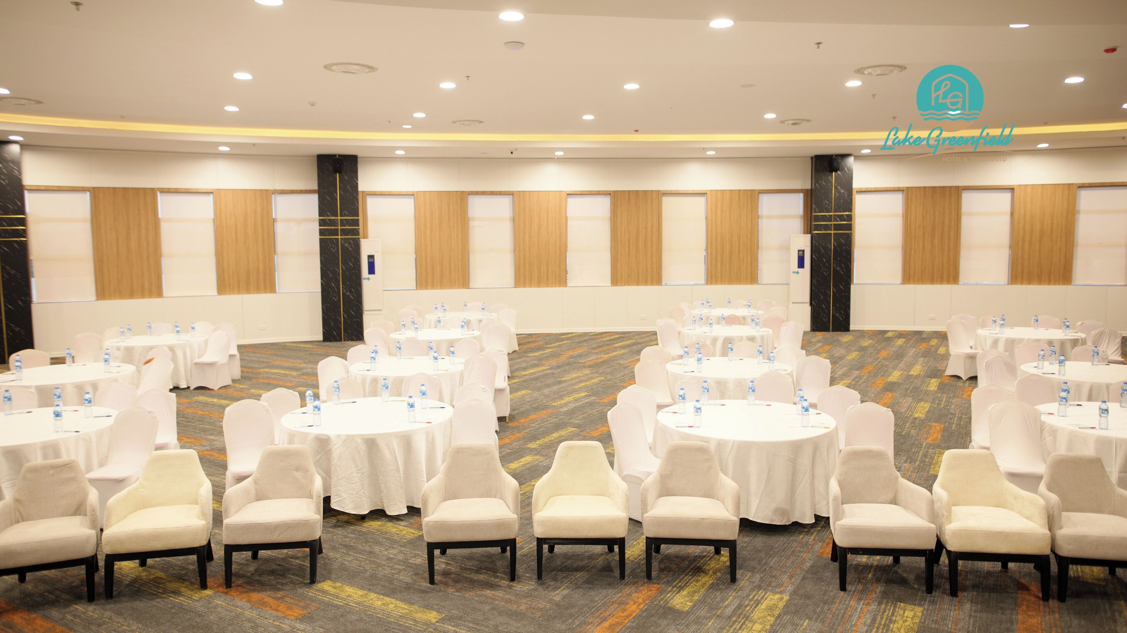 A conference room with round tables, white chairs, and water bottles.