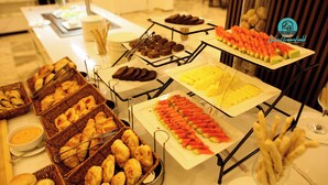 A buffet with various food items including pastries, fruits, and desserts.