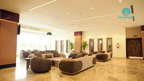 A modern hotel lobby with a seating area, large windows, and a fire extinguisher on the wall.