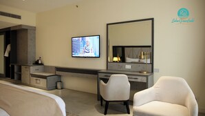 A hotel room with a bed, a desk, a chair, a television, and a large mirror.