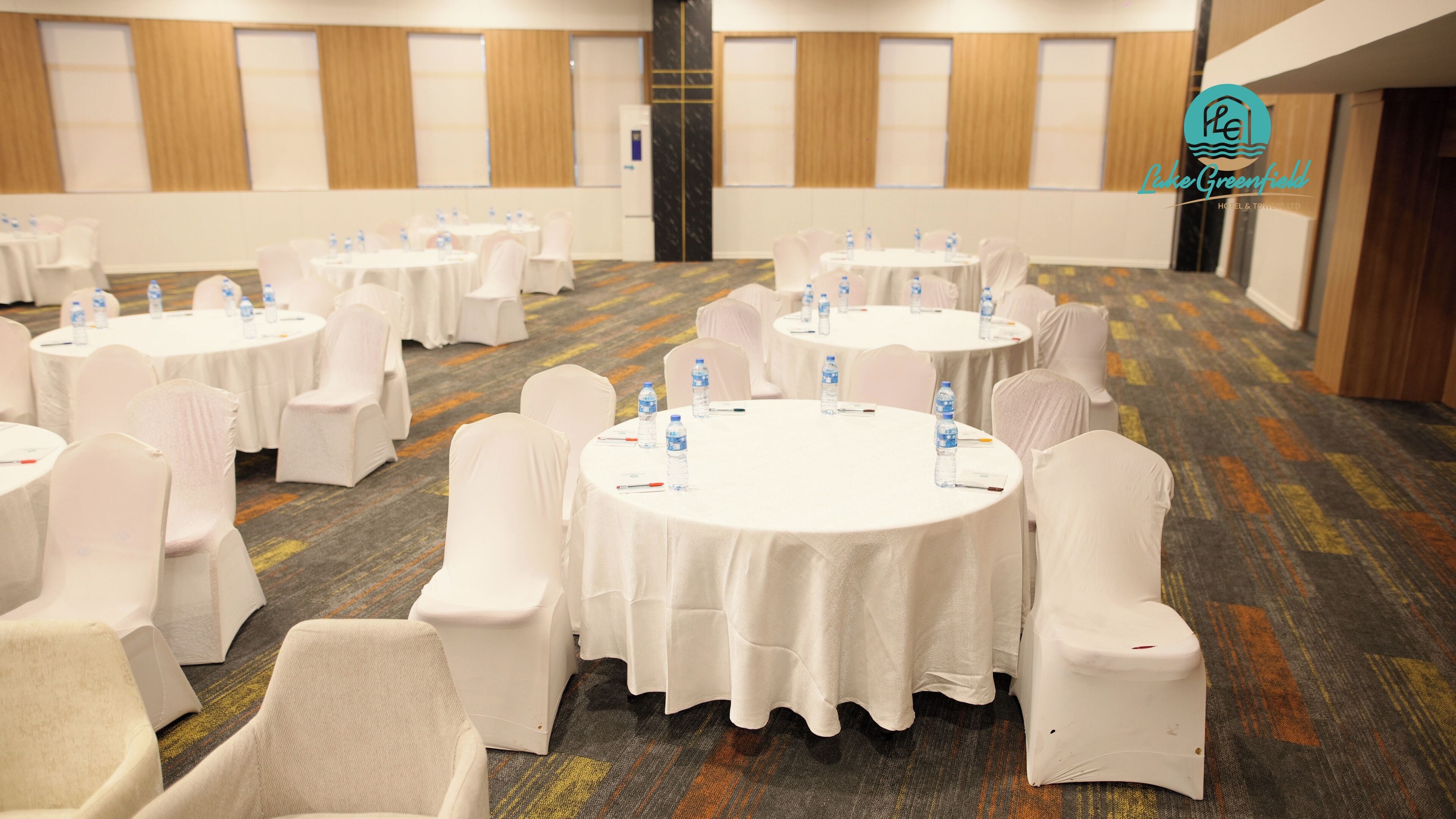 A conference room with round tables, white chairs, and water bottles.