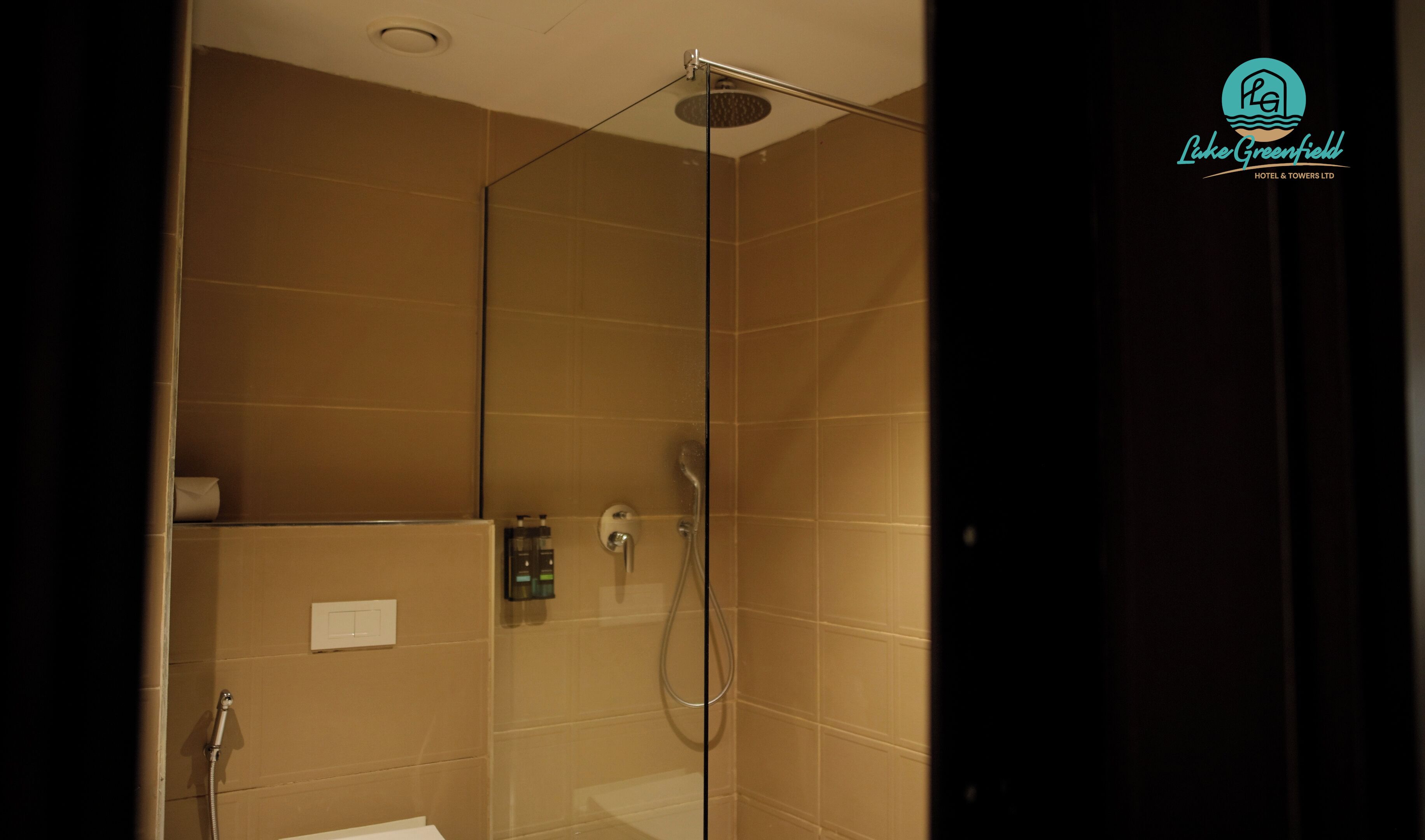 A glass-enclosed shower with a handheld showerhead and a wall-mounted control panel.