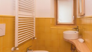 A bathroom with a toilet, bidet, sink, and a window with blinds. - Peace in the nature close to Palazzo Vertemate, Madesimo and Engadina. (Lombardia)