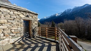 A stone building with a wooden balcony overlooking a mountainous landscape. - Peace in the nature close to Palazzo Vertemate, Madesimo and Engadina. (Lombardia)