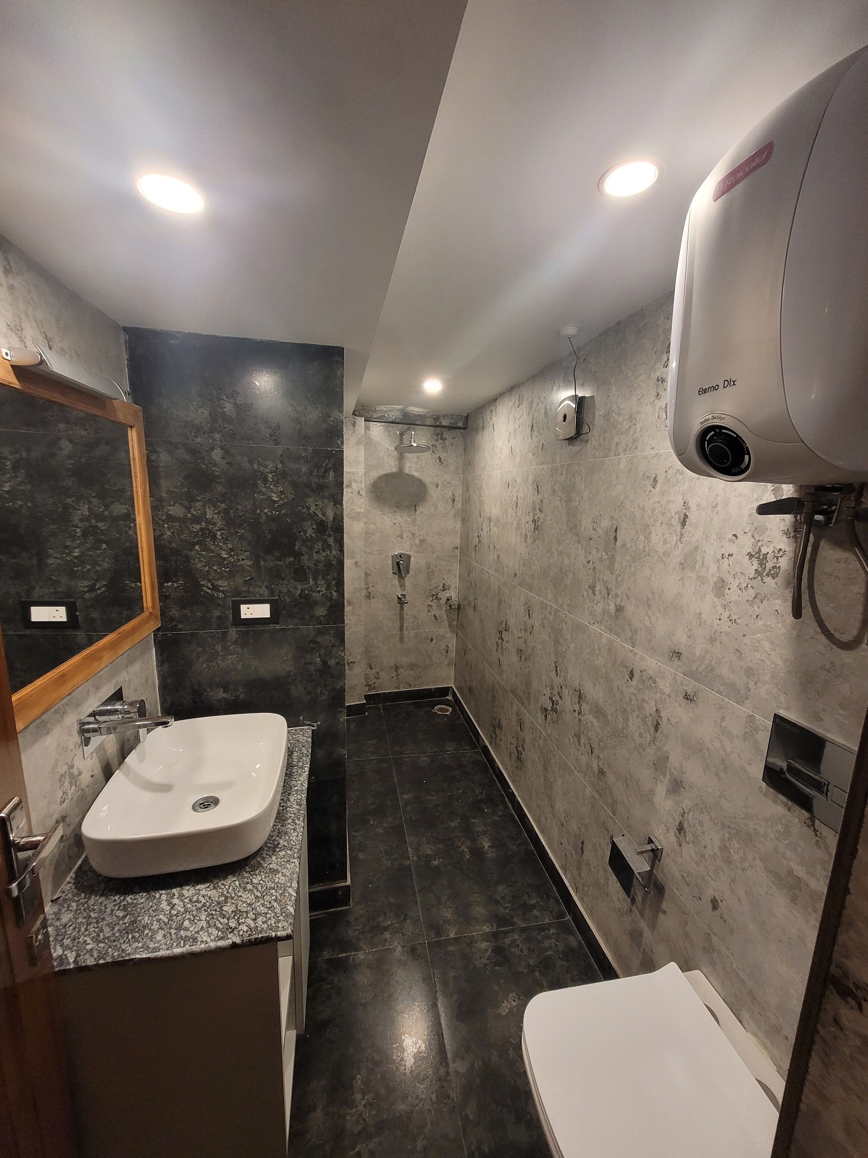 Een moderne badkamer met een groot wastafel, toilet en douche.