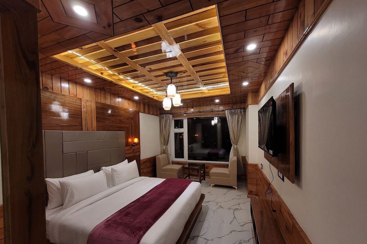 A modern bedroom with a large bed, a TV, and a window with curtains.