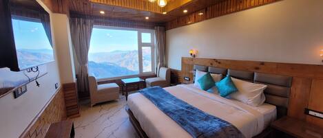 Un dormitorio con una cama grande, un escritorio y una ventana con vistas a la montaña.