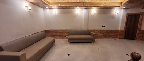 Una habitación amplia con techo de madera, un candelabro, un sofá y un banco de madera.