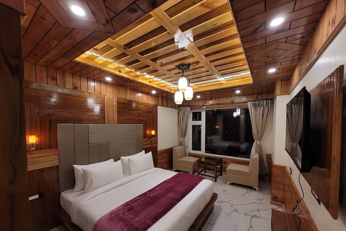 Un dormitorio con paneles de madera, una cama, un escritorio y un ventanal grande.