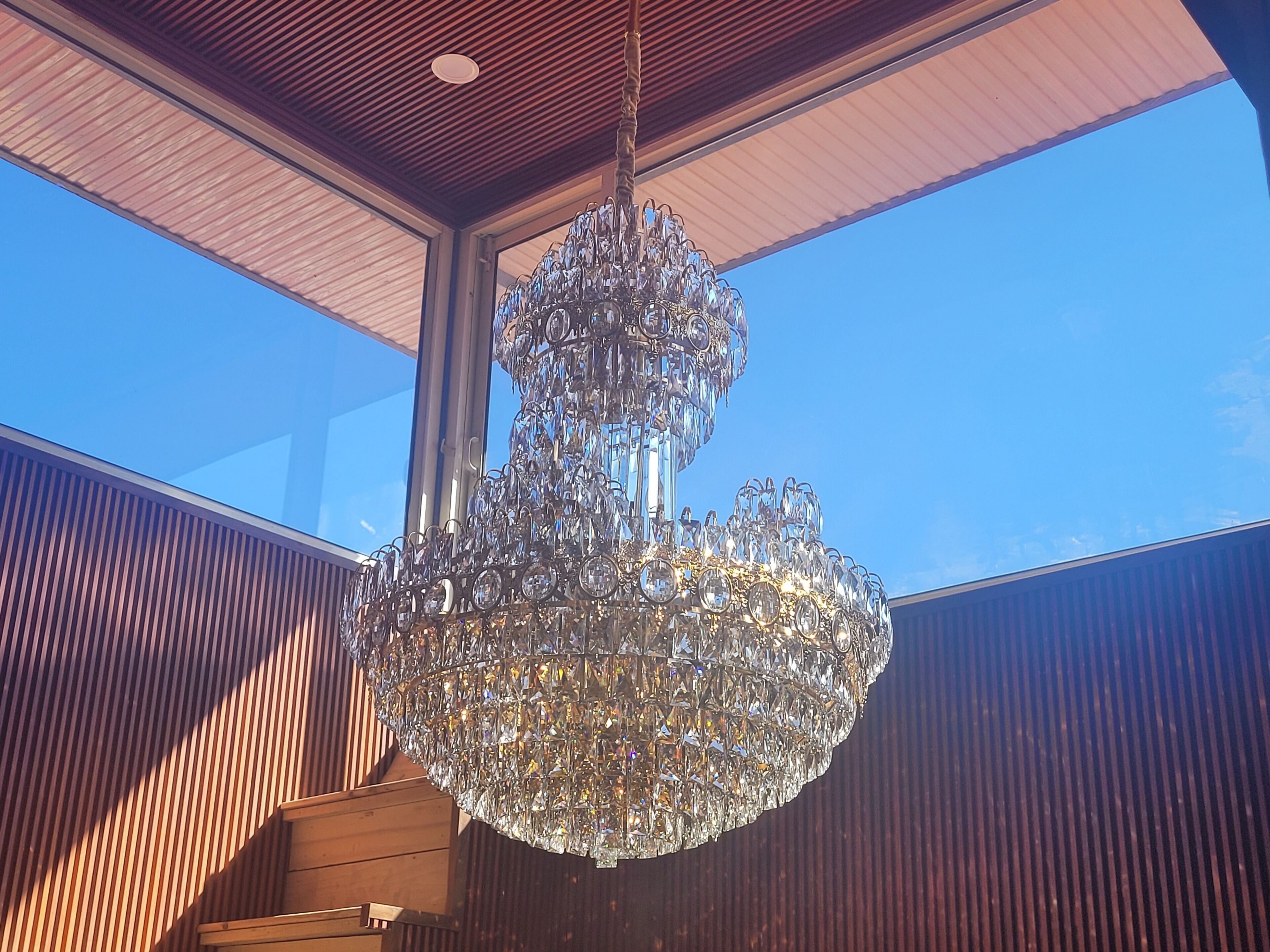 A large, ornate crystal chandelier hanging from a wooden ceiling structure.