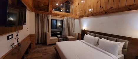 A wooden-paneled room with a bed, a TV mounted on the wall, and a desk with a chair.