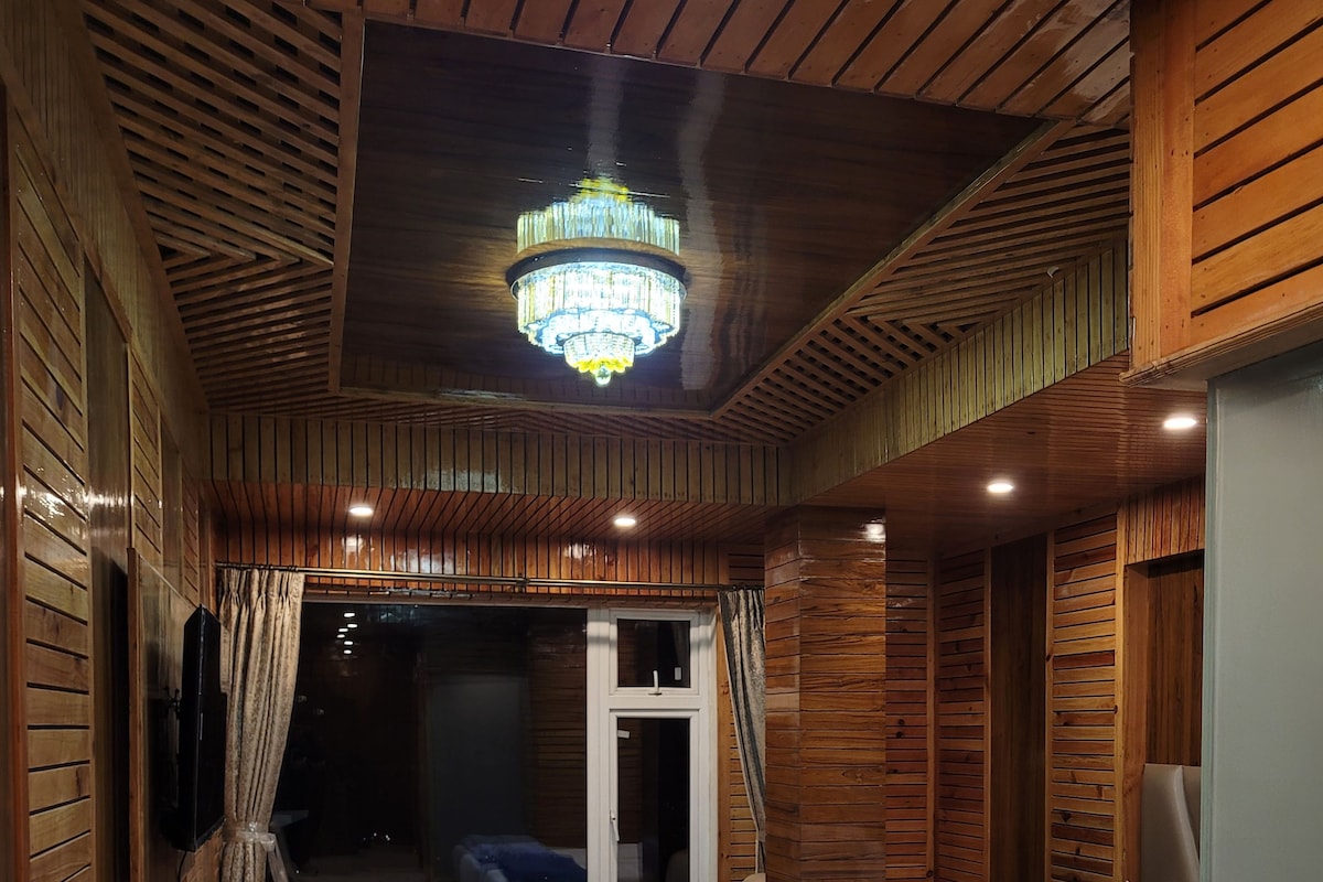 A wooden room with two beds, a small table, and a window.