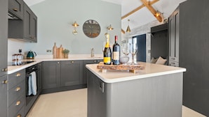 A modern kitchen with dark grey cabinets, a central island, and a clock on the wall.
