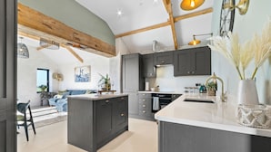 A modern kitchen with dark cabinetry, a large island, and pendant lighting.