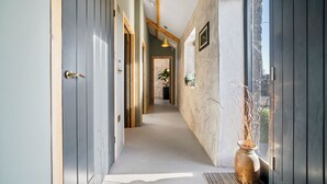 A hallway with a wooden ceiling, a large window, and a vase with branches.