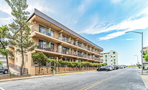 A multi-story hotel with balconies, a parking lot, and a clear sky.