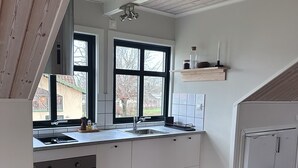 A modern kitchen with white cabinets, a black countertop, a built-in oven, and a large window. - Cozy apartment in own house with terrace near Lassalyckan (Västra Götalands län)