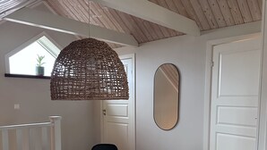 A dining area with a round table, black chairs, a woven pendant light, a large mirror, and wooden flooring. - Cozy apartment in own house with terrace near Lassalyckan (Västra Götalands län)