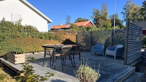 A wooden deck with outdoor furniture, a potted plant, and a wooden fence. - Cozy apartment in own house with terrace near Lassalyckan (Västra Götalands län)