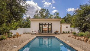 Une maison moderne dotée d’une piscine, d’un patio avec mobilier d’extérieur et d’un jardin.