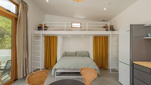 Une chambre compacte et moderne, équipée d’un lit superposé, d’une petite table à manger et d’un réfrigérateur.