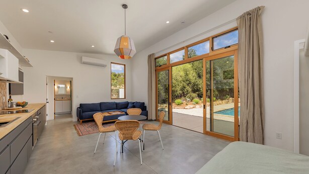 Une cuisine moderne avec un coin repas, un canapé et une vue sur une piscine.