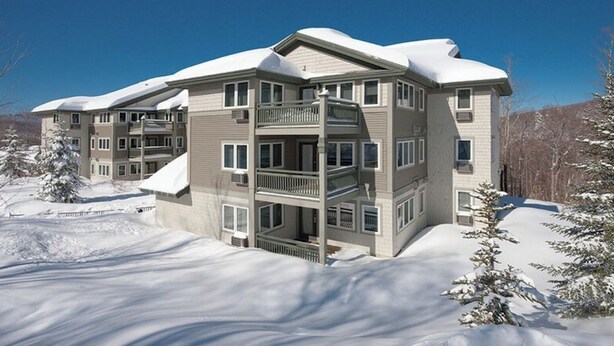 A multi-story hotel with a central atrium, balconies, and a snow-covered landscape. - Beautiful Deluxe 2 Bedroom Condo in Smugglers Notch Resort (Jeffersonville)