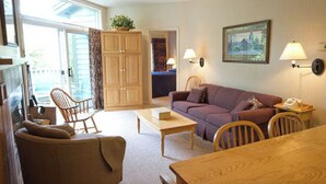 A cozy living room with a sofa, chairs, a coffee table, and a wooden cabinet. - Beautiful Deluxe 2 Bedroom Condo in Smugglers Notch Resort (Jeffersonville)